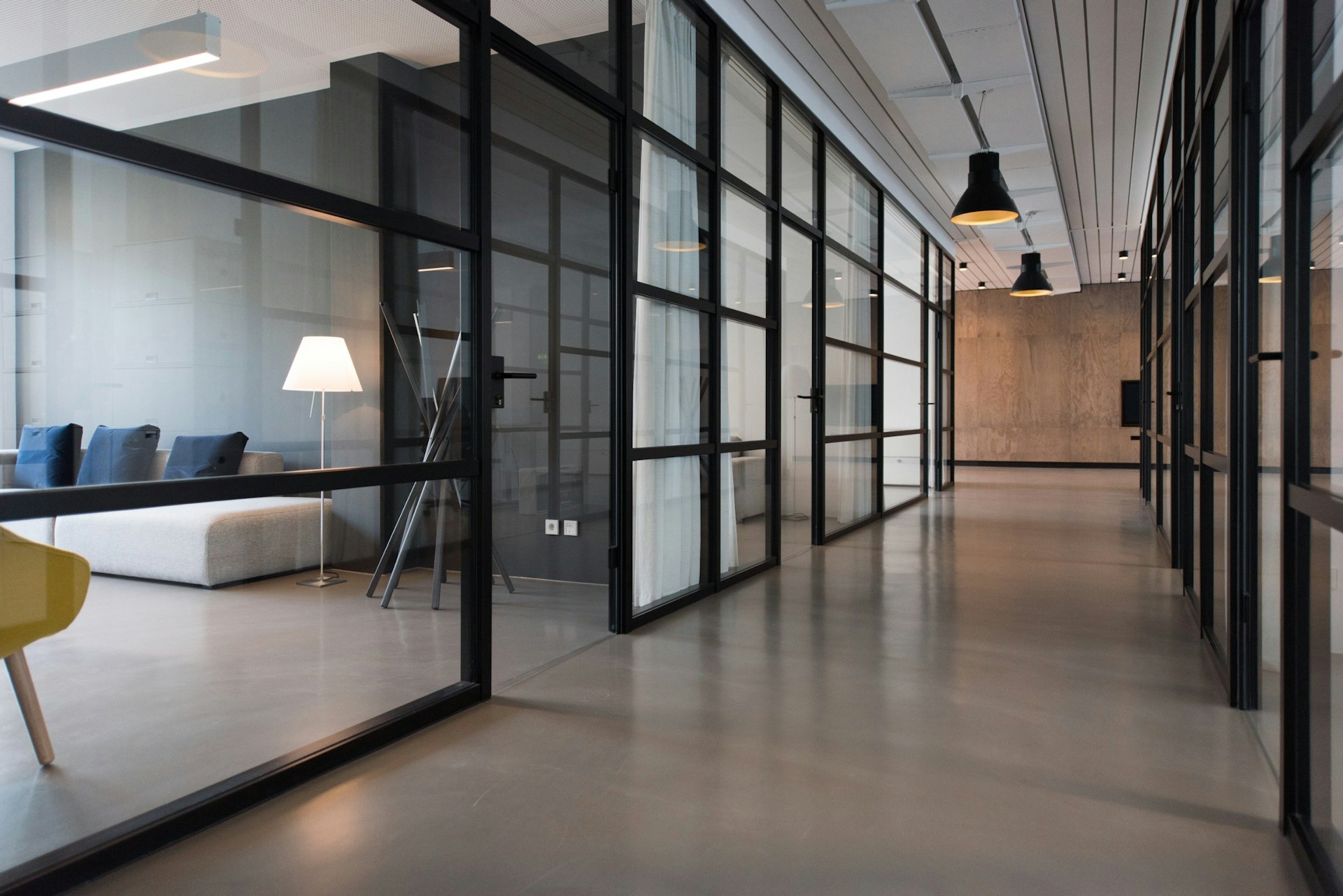Glass-walled office meeting rooms beside a clean corridor